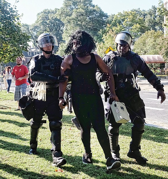 Police detain an unidentified counterprotester for singing rap music using a microphone and speaker on the grassy median on Monument Avenue between Meadow Street and Allen Avenue. With a semiautomatic rifle over his shoulder, CSA II organizer Thomas Crompton of Tennessee argues his point of view