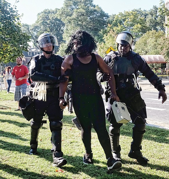 Police detain an unidentified counterprotester for singing rap music using a microphone and speaker on the grassy median on Monument Avenue between Meadow Street and Allen Avenue. With a semiautomatic rifle over his shoulder, CSA II organizer Thomas Crompton of Tennessee argues his point of view