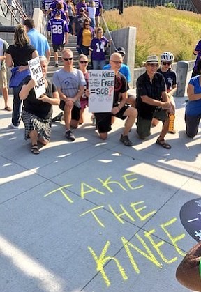 Protesters stand outside US Bank Stadium in Minneapolis to take a knee in solidarity with the team.