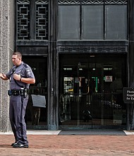 Beatrice Downs is confronted Friday by a Capitol Police officer as she pickets in front of the Patrick Henry Building in Capitol Square. She is told her demonstration on the state sidewalk is not allowed. 