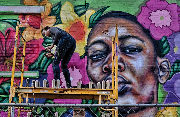 Cityscape // A colorful new mural celebrating women now decorates the 1st Street side of a Downtown building at 1st and Broad streets. Left, Austin Miles puts finishing touches on the mural last Saturday. The mural is the creation of Richmond artist Hamilton Glass in partnership with Girls For A Change, a nonprofit that seeks to inspire and support African-American girls and girls of color to achieve their dreams. 