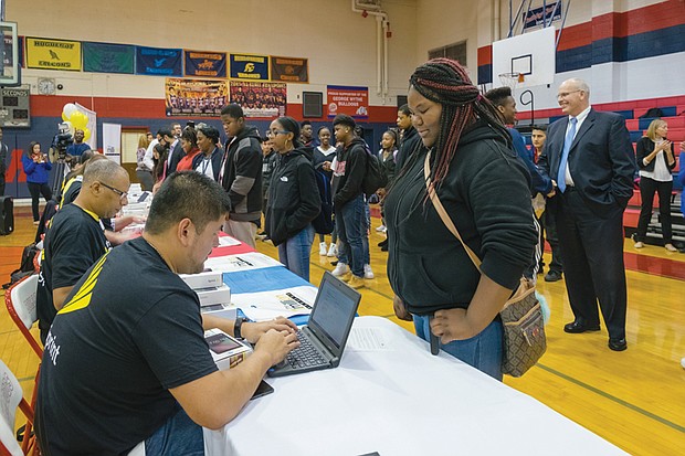 Bridging the digital divide //
Ta’Niyah Brown, right, is one of 1,050 Richmond high school freshmen receiving a new, internet-connected computer tablet, courtesy of Sprint. Watching the distribution at George Wythe High School, is interim schools Superintendent Thomas E. “Tommy” Kranz, far right. Officials from the wireless communication company and its foundation gave students the free equipment and wireless service at the Oct. 19 event. Through the next four years, a total of 5,250 city students who lack computers and internet service at home will receive electronic tablets to help them do their homework. The distribution is part of the company’s 1Million Project that seeks to close the digital divide that makes it difficult for students to achieve academic success. 