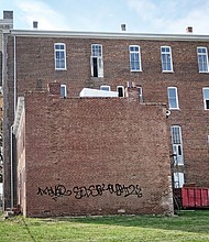 Graffiti mars bricks on the annex to the historic St. Luke Building at 900 St. James St. in Gilpin Court. Now vacant, the annex provided housing for visiting agents of the former Independent Order of St. Luke. The owners lack permits to fence both buildings.   