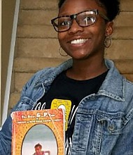 Jordyn Alexis Ash, the granddaughter of author Tyrone Ash, holds a copy of his book