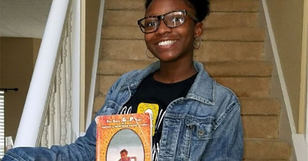 Jordyn Alexis Ash, the granddaughter of author Tyrone Ash, holds a copy of his book