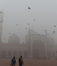Indian visitors walk through the courtyard of Jama Masjid amid heavy smog in the old quarters of New Delhi on November 8, 2017.
