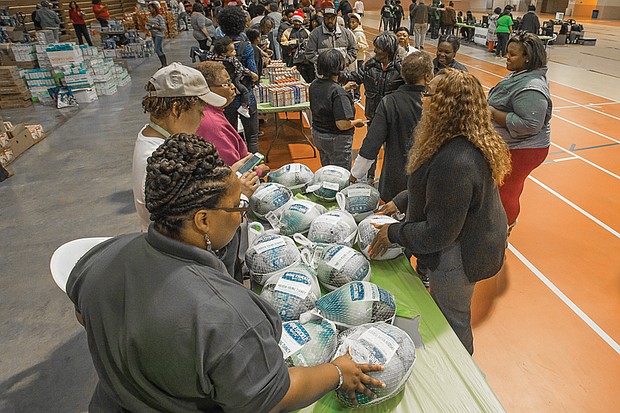 Thanksgiving blessings // more than 2,000 Richmond area families received turkeys, boxes of stuffing and canned goods at the Thanksgiving Harvest sponsored Nov. 16 by St. Paul’s Baptist Church and two dozen area churches, sororities, professional and nonprofit organizations at the Arthur Ashe Jr. Athletic Center on the Boulevard. Left, Richmond Police Officer Charles Battle delivers a Thanksgiving basket on Monday to Percelle Smith’s family in Hillside Court.