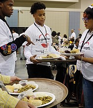 Holiday sharing // Volunteers Malik Childs, left, Sidney Evans, Davon Courtney and Shonda Harris-Muhammed prepare to serve meals at the Giving Heart Community Thanksgiving Feast at the Greater Richmond Convention Center. 