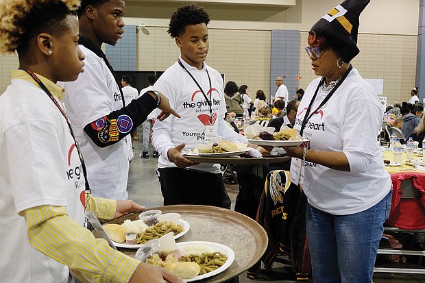 Holiday sharing // Volunteers Malik Childs, left, Sidney Evans, Davon Courtney and Shonda Harris-Muhammed prepare to serve meals at the Giving Heart Community Thanksgiving Feast at the Greater Richmond Convention Center. 