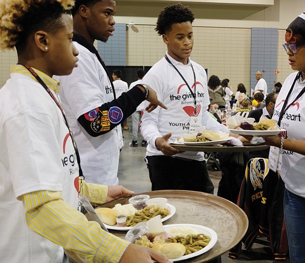Holiday sharing // Volunteers Malik Childs, left, Sidney Evans, Davon Courtney and Shonda Harris-Muhammed prepare to serve meals at the Giving Heart Community Thanksgiving Feast at the Greater Richmond Convention Center. 