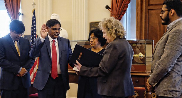 Joseph F. Thekkekara is sworn in as Richmond’s new postmaster Wednesday in the Old House Chamber at the State Capitol. Previously a postmaster in Texas, Illinois and New York communities, he is the 34th person to hold the title in Richmond since the beginning of the postal service around 1778. He is surrounded by family, from left, son Jason, wife Annie and son Justin as the oath of office is administered by Linda Malone, U.S. Postal Service vice president for the Capital Metro area, which stretches from Baltimore to Atlanta. Mr. Thekkekara started his career as a mail carrier in 1988. He succeeds Harold G. O’Connor, who was postmaster for 11 years before being removed in 2016 and retiring earlier this year in the wake of a scandal over management efforts to reduce carrier overtime pay by changing time cards.