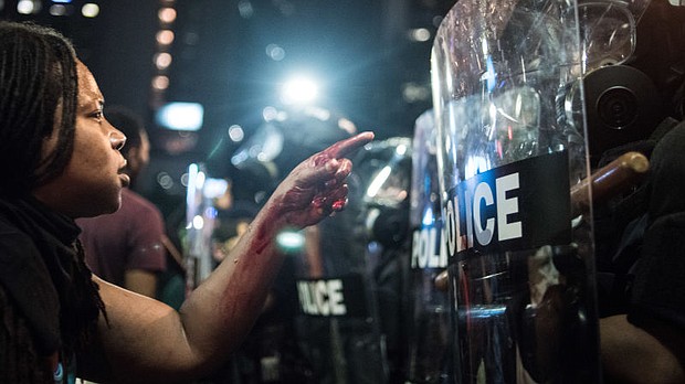  With blood covering her hand and arm, a woman points at a police officer on September 21, 2016 in Charlotte, NC. (Sean Rayford/Getty Images)