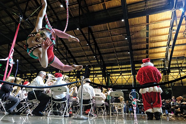 Mina Corbeau, a performer with Host Of Sparrows Aerial Circus, thrills spectators, below, along with Santa and the band at Main Street Station. 