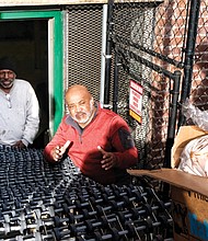 Bringing in the loaves //
Dr. Alonza L. Lawrence, right, pastor of Moore Street Missionary Baptist Church, and church member James Moses await a box filled with bread to make its way down a conveyor belt and into the church’s old social center on Monday morning. The two were helping to stock the food pantry at the Leigh Street church in the Carver neighborhood. The food delivery was from FeedMore, the hunger alleviation organization that serves Central Virginia. The church distributes free bags of groceries to all who stop by from 3 to 4 p.m. every Monday, except the next two — Christmas Day and New Year’s Day.
