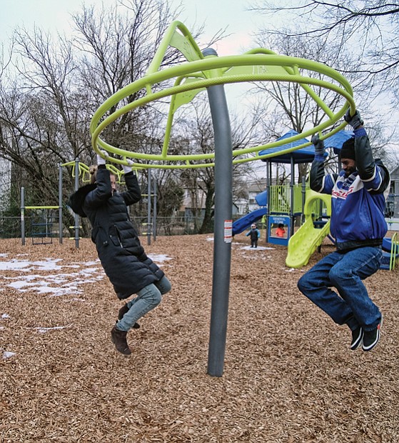 Monica and Barry Gamble, try out a ring swing on the new “Tot Lot” last Friday at the city’s newest playground for children. Location: 2001 3rd Ave. in North Side’s Highland Park. The city Department of Parks, Recreation and Community Facilities developed the playground. 