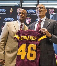 Former NFL coach turned sportscaster Herm Edwards, right, receives a jersey for his new coaching job at Arizona State University from Athletic Director Ray Anderson. 