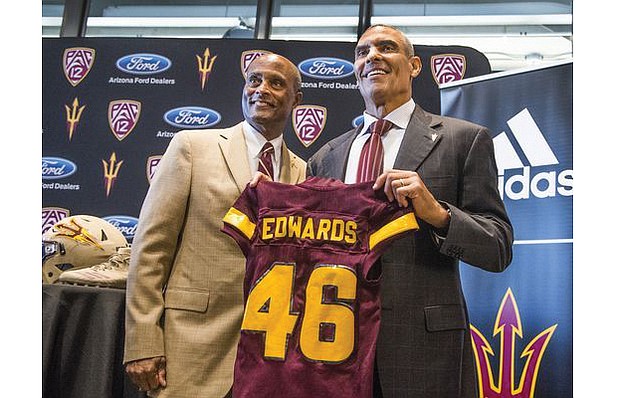 Former NFL coach turned sportscaster Herm Edwards, right, receives a jersey for his new coaching job at Arizona State University from Athletic Director Ray Anderson. 