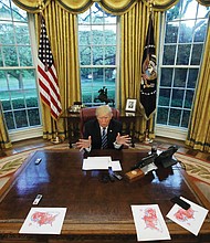 President Trump speaks during an Oval Office interview with Reuters in late April. He had printed maps of the United States showing areas of red where he won during the November 2016 presidential election.