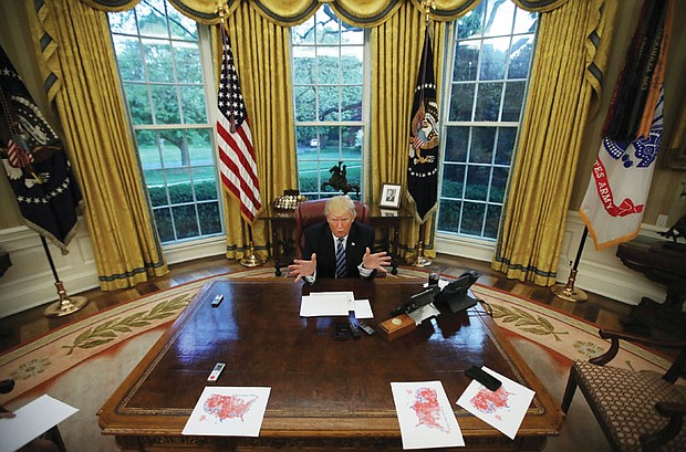 President Trump speaks during an Oval Office interview with Reuters in late April. He had printed maps of the United States showing areas of red where he won during the November 2016 presidential election.