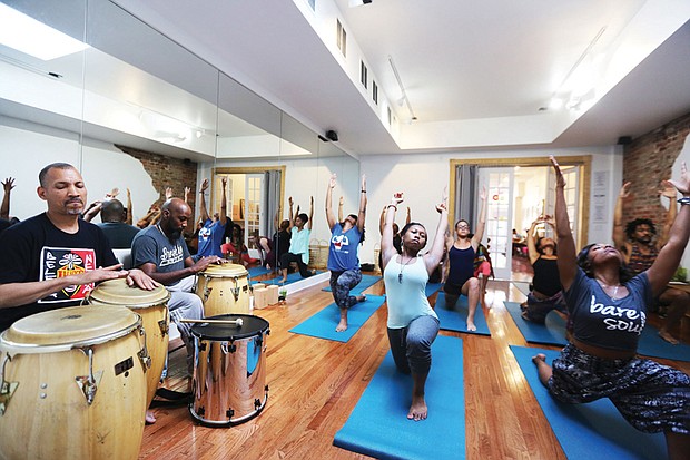 Ram Bhagat, left, and his drum circle set the beat for a yoga session in June at a Jackson Ward juice and yoga bar.