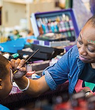 Kelita Wooten, bottom right, paints the face of a youngster during the festivities that included speakers, workshops and children’s activities.