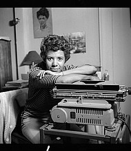 Lorraine Hansberry leans over her typewriter in her Greenwich Village apartment on Bleecker Street during her April 1959 photoshoot for Vogue. Photo by David Attie.