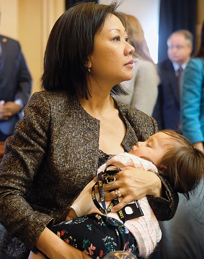 Fairfax Delegate Kathy Tran takes in the action on her first day as a legislator while her less than impressed baby, Elsie, naps.  
