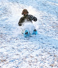 Slippery slope  //
Jamon Lewis, 11, makes the snow fly as he slides down a steep slope at Forest Hill Park in South Side last Friday. The snow created fun, but also icy conditions that led school systems in the Richmond area to close through Tuesday. Classes resumed Wednesday. The cold and ice also caused power outages and froze water pipes in untold numbers of homes and businesses. Underground water infrastructure also cracked, shutting off the water supply in Church Hill, parts of Downtown and in nearby suburbs. On Monday and Tuesday, cracked water mains twice caused partial closure of Interstate 95 in Richmond as water flooded the highway.