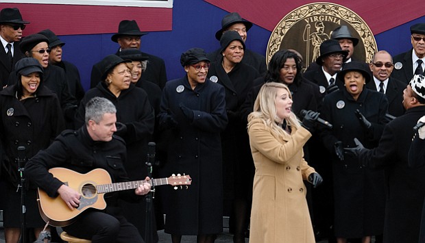 Larry Bland and the Volunteer Choir accompany the mother-daughter country group, Marna & Macy, in the final song at the inaugural ceremony. They are, from right, Marna Bales; her daughter, Macy Kaczmarek, center; and Ms. Bales’ husband, Jody Boyd, on acoustic guitar. 