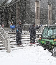 City workers clear the steps and sidewalk outside Richmond City Hall during a March 2014 snowstorm.
