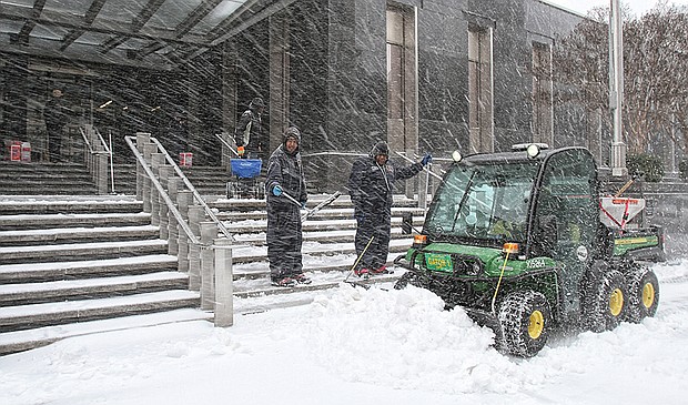 City workers clear the steps and sidewalk outside Richmond City Hall during a March 2014 snowstorm.
