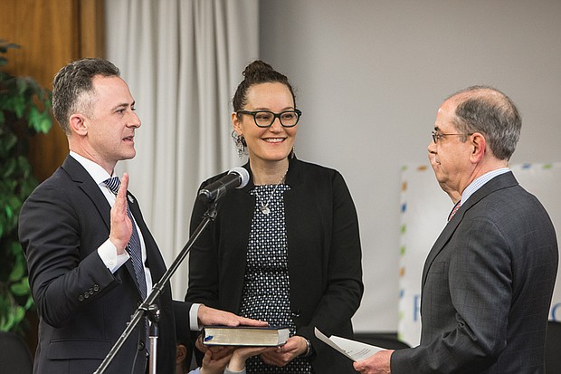 Jason Kamras, left, is sworn in as Richmond’s new schools superintendent as his wife, Miwa, holds his late grandfather’s Torah. Performing the ceremony on Feb. 1 is Edward F. Jewett, clerk of the Richmond Circuit Court. 

