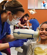 Working for smiles //
Kate Norbo, a Virginia Commonwealth University dental student, uses a portable X-ray machine to take images of Taylor Deane’s teeth during the youngster’s Feb. 2 dental exam. “Give Kids a Smile” was the theme of the one-day event launched by the American Dental Association. The VCU School of Dentistry participated, providing no-cost dental services to area children.  