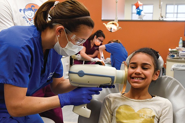 Working for smiles //
Kate Norbo, a Virginia Commonwealth University dental student, uses a portable X-ray machine to take images of Taylor Deane’s teeth during the youngster’s Feb. 2 dental exam. “Give Kids a Smile” was the theme of the one-day event launched by the American Dental Association. The VCU School of Dentistry participated, providing no-cost dental services to area children.  