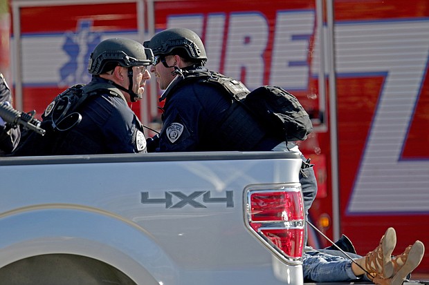 Police officers tend to a victim as they ride in the back of a pickup truck. John McCall/Sun Sentinel/TNS/Getty Images