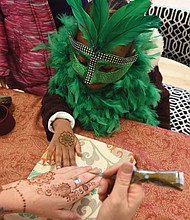 After donning a mask and feather boa, 4-year-old Marshall Howard gets a henna tattoo during the main event inside the center on West 15th Street. Music, performances by several groups and Cajun-style food were featured, along with a King Cake.