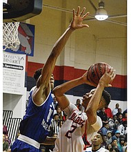 John Marshall High School’s Isaiah Todd, left, stretches to block a shot by George Wythe High’s Darrell Purdie during last Friday’s regional final. While John Marshall won the game 83-64, both teams will play in the state quarterfinals this weekend.