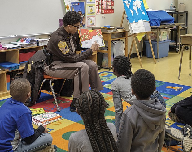 The joy of reading // Adults are spreading the joy of reading to area children. Left, Richmond Sheriff Antionette V. Irving reads to students at Overby-Sheppard Elementary School in North Side on Tuesday
