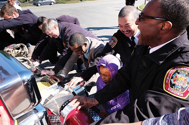 All hands on deck // 
Richmond Fire Chief Melvin Carter, right, leads the charge to push a new fire truck into its new berth at Station 14 at 2932 Hawthorne Ave. in North Side. Among those helping during the traditional housing ceremony Saturday were Mayor Levar M. Stoney and 6-year-old Noah Ashe, whose family lives in a home just doors away from the station. Noah attended the ceremony with her dad, Jonathan Ashe, and year-old brother, David.