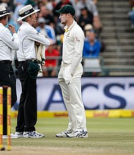 Australian fielder Cameron Bancroft (R) is questioned by Umpires Richard Illingworth and Nigel Llong during the third day of the third Test cricket match between South Africa and Australia on March 24, 2018 in Cape Town./ Gianlugi Guercia/AFP/Getty