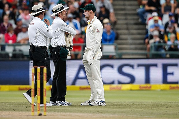 Australian fielder Cameron Bancroft (R) is questioned by Umpires Richard Illingworth and Nigel Llong during the third day of the third Test cricket match between South Africa and Australia on March 24, 2018 in Cape Town./ Gianlugi Guercia/AFP/Getty