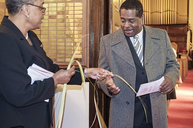 Bessie Banks, an usher at Riverview Baptist Church in Richmond’s West End, hands Peter Rawlins a palm after the service on Palm Sunday.