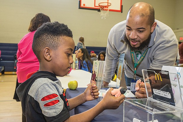 Better health //
Elijah Kersey, 5, squeezes a pliable figure of a sumo wrestler as he visits with Jaquelle Scott at the Second Chances Comprehensive Services booth last Saturday at the annual Virginia Commonwealth University Wellness Block Party. The event, held at Martin Luther King Jr. Middle School in the East End, offered health screenings, information and consultations with health professionals. It was the 11th year for the community event put on by VCU students with the assistance of physicians and community organizations. Second Chances provides mental health counseling for youths and adults, case management and links to other community resources.