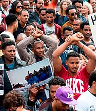 African migrants demonstrate with their hands crossed outside the Embassy of Rwanda in the Israeli city of Herzliya on February 7, 2018.