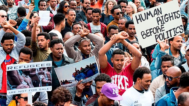 African migrants demonstrate with their hands crossed outside the Embassy of Rwanda in the Israeli city of Herzliya on February 7, 2018.