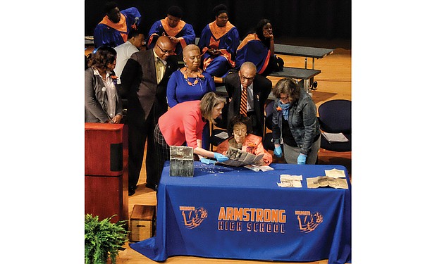 Former schools Superintendent Lucille M. Brown, seated center, an Armstrong High School alumna, describes for the audience the contents of the 1952 time capsule found during demolition of the former Armstrong building on 31st Street. Dr. Brown is flanked by Meg Hughes, left, of The Valentine museum and architectural historian Kimberly Chen who were handling the fragile items. Looking on are, from left, Armstrong Principal Willie Bell, School Board member Cheryl L. Burke and Dennis H. Harvey, chair of the Armstrong High School Alumni Coalition.