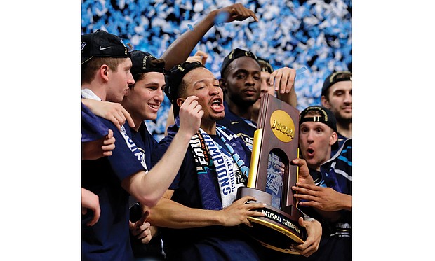 Villanova University’s Jalen Brunson, center, holds the championship trophy with teammates after beating the University of Michigan 79-62 on Monday to win the NCAA men’s title.