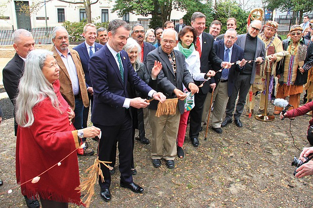 Gov. Ralph S. Northam cuts the ribbon dedicating “Mantle,” the new monument honoring Virginia’s Native American tribes, during a ceremony Tuesday. Among the dignitaries are, from Gov. Northam’s left, Frances Broaddus-Crutchfield of the Virginia Indian Commemorative Commission; Ken Adams, chief emeritus of the Upper Mattaponi tribe; former Virginia First Lady Susan Allen and her husband, former Gov. George Allen. Monument designer Alan Michelson also is in the crowd. Below, An infinity fountain with a black marble top inscribed with the names of Virginia’s Native American tribes is the centerpiece of the new monument in Capitol Square.