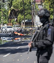 An Indonesian anti-terror policeman stands guard at the site of one of the bombings Sunday.