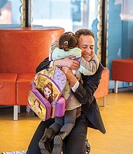 Mr. Kamras kneels to hug a student at the start of the school day. 